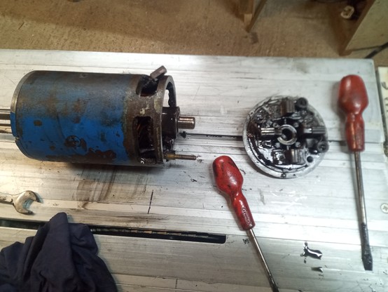 Partially disassembled (and filthy) starter motor on a bench.