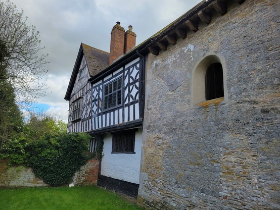 External view of Odda's Chapel, Deerhurst. The image shows the wall of the Saxon chapel abutting the C17th timber farmhouse that it became part of.