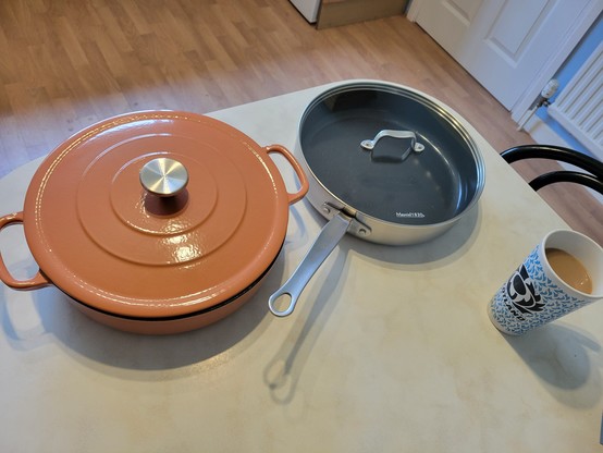Two saucepans, on the left a Le Creuset-style cast iron and enamel two-handled casserole dish, on the right a stainless steel heavy based frying-type pan with a long handle and clear lid.