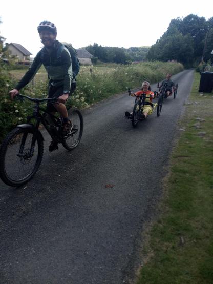 The people from the wheelchairs riding the handcycles (quite fast) down a narrow rural road.