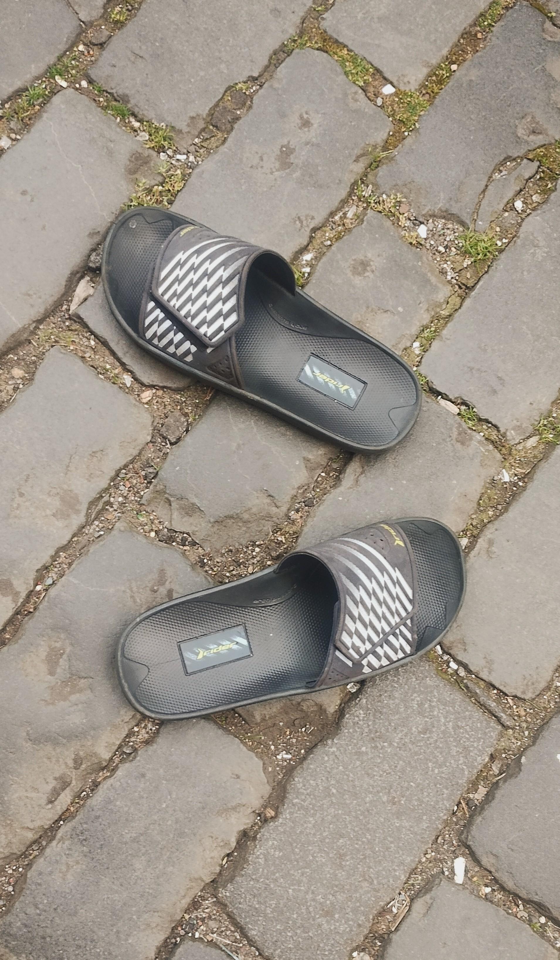 A pair of black sandals just sitting on a cobbled street