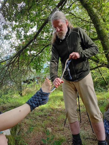 Me tying a closely interwoven rope boot on someone's foot, from which they will be suspended.